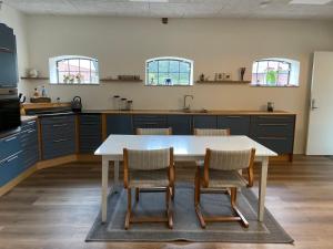 a kitchen with a white table and chairs in it at Højmosegård ÅBENT HEMS in Varde