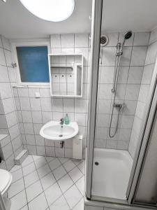 ein weißes Badezimmer mit Waschbecken und Dusche in der Unterkunft Apartment with kitchen, bed, sofa in Essen