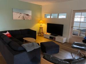 a living room with a couch and a flat screen tv at Højmosegård ÅBENT HEMS in Varde
