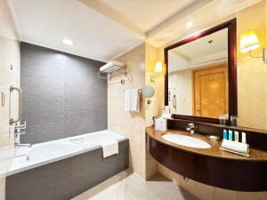 a bathroom with a sink and a tub and a mirror at The Bellevue Manila in Manila +26 photos