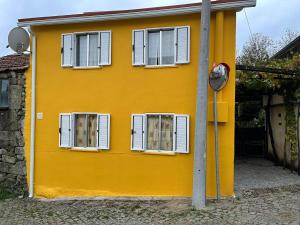 a yellow house with white windows and a meter at Casa das bonecas in Castro Daire +4 photos