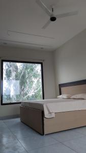 a bedroom with a large bed and a large window at Aanandam Hotel in Babarpur