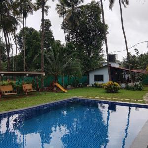 a swimming pool in front of a house with palm trees at Disha Villa in Alibag
