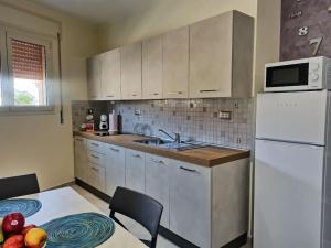 a kitchen with white cabinets and a white refrigerator at Le Nonne HOUSE - Assemini - free parking P in Assemini