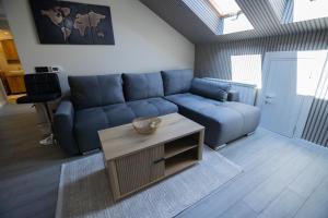 a living room with a blue couch and a table at Aqua Lux apartmani 1 in Vršac