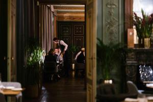 Ein Mann, der im Flur steht, mit Leuten, die an Tischen sitzen. in der Unterkunft Corneli Residenties - Chateau St Gerlach in Valkenburg + 27 Fotos