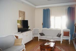 a living room with white furniture and a flat screen tv at Hibe Dede Cappadocia in Ürgüp