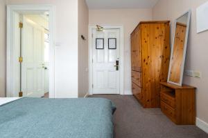ダブリンにあるCompact Ensuite Room In Heart Of Georgian Dublinのベッドと木製のキャビネットのある寝室