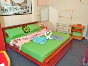 a bedroom with a large green bed with towels on it at Hotel Kingland in Ruwanwella