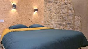 a bedroom with a blue bed with a stone wall at Maison FLOËGE 4 personnes in Burzet