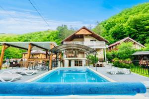 a house with a swimming pool in front of a house at Casa de Vis Băișoara -Cab Mircea -Cab Gaby in Băişoara