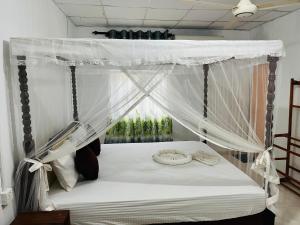 a bedroom with a canopy bed with white curtains at Nature Lover's Inn in Tangalle