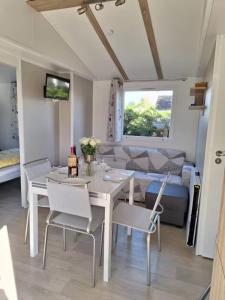 a dining room with a table and chairs and a couch at Mobile home with shared pool in Saint-Arnoult in Saint-Arnoult