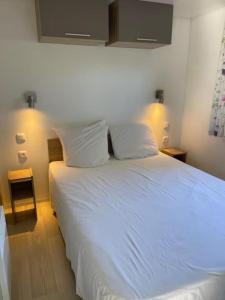 a white bed in a room with two lamps at Mobile home with shared pool in Saint-Arnoult in Saint-Arnoult +11 photos