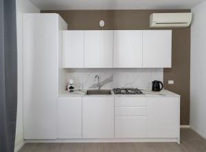 a white kitchen with white cabinets and a sink at Casa Sambò in Chioggia