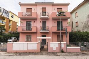 リミニにあるAmazHome - Il Rifugio degli Artistiのバルコニーと駐車場のあるピンク色の建物