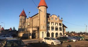 a large building with cars parked in front of it at Dvorac Kastel in Ljubače