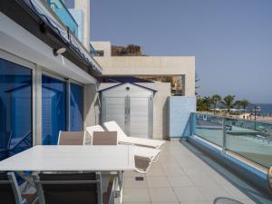 a balcony with a white table and chairs on a building at Blue Horizon Mogan in Puerto de Mogán