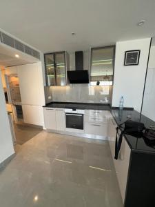 Una cocina con gabinetes blancos y una encimera negra. en 2BR Haut Standing Avec Piscine Face Hôtel Movenpick Sousse, en Sousse