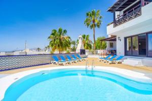 une piscine avec des chaises longues et une maison dans l'établissement Villa Speranza by Villa Plus, à Puerto del Carmen