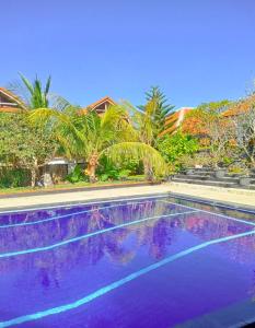 een paars zwembad met palmbomen op de achtergrond bij Villa Lumbung Uluwatu 1 in Uluwatu