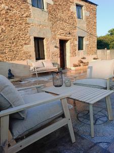 a patio with a wooden table and chairs and a building at Dona Remedios in Xermade