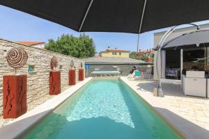 a swimming pool in front of a house with an umbrella at Ferienhaus mit Privatpool für 6 Personen ca 130 qm in Kanfanar, Istrien Binnenland von Istrien in Kanfanar +14 photos