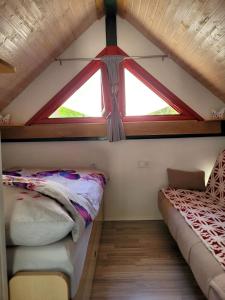 two beds in a small room with a window at Babičina hišica in Mišji Dol