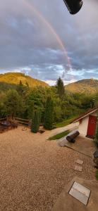 a rainbow in the sky over a yard with a house at Babičina hišica in Mišji Dol