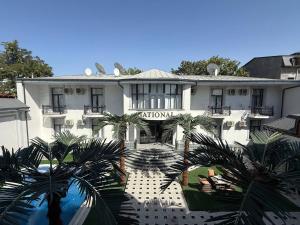 un edificio bianco con palme di fronte di National Gold Plaza a Samarkand