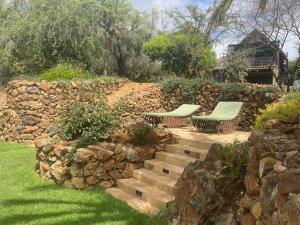 a garden with two benches and a stone wall at O'Leleshwa Retreat in Naivasha