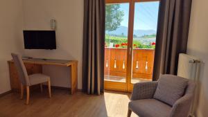 a room with a desk and a television and a balcony at Landgasthof Sonnegghof in Castelvecchio