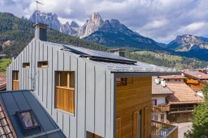 una casa con tetto con montagne sullo sfondo di Ciasa Nü - Piano Rialzato a Pozza di Fassa