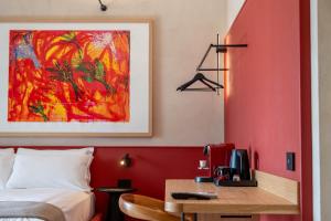 a bedroom with a red wall with a bed and a desk at Casa Tre Archi - Camere Luxury in Altamura +14 photos
