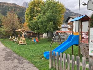 un cortile con parco giochi, scivolo e altalene di Ciasa Nü - Piano Rialzato a Pozza di Fassa