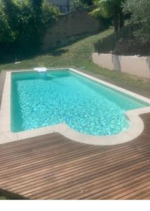 a large blue swimming pool with a wooden deck at Typic House - Maison piscine CLIM et VUE in Albi