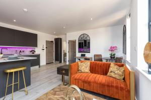 an open kitchen and living room with an orange couch at Sussex House 20 - Artistic Luxe 1 Bed Apartment in Horsham