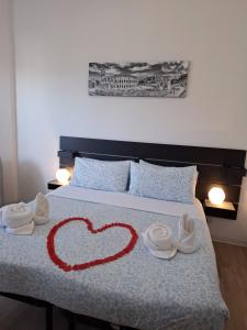 罗马Roma Trastevere Holiday的床上有一颗心，上面放着毛巾和鞋子