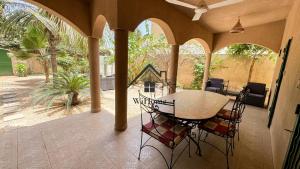 a porch with a table and chairs on a patio at Villa Gallé Kouley bord de mer in Somone