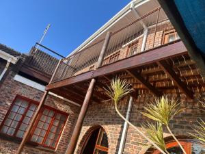 a brick building with a balcony and palm trees at B and G Haven in King Williamʼs Town