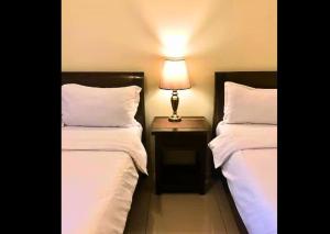 duas camas em um quarto com um abajur sobre uma mesa em Need Place To Stay Wake Up to Breathtaking Taal Views from Your Window I Tagaytay Getaway em Kaybagal