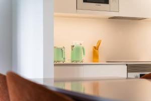 フンシャルにあるGuestReady - Acqua residencesのテーブルと2つの緑色の家電製品を備えたキッチン