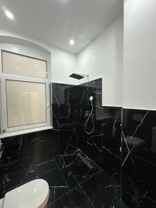 a bathroom with black tiled walls and a window at Nook - Zentrale Lage - an der ListerMeile in Hannover