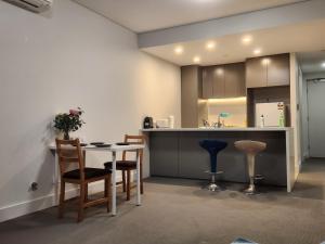 a kitchen with a table and chairs and a counter at Skyline Comfort - Sydney Olympic Park in Sydney