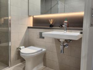 a bathroom with a white sink and a toilet at Skyline Comfort - Sydney Olympic Park in Sydney +6 photos