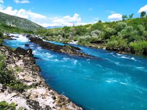 a river with blue water and trees in the background at Rayand in Mostar