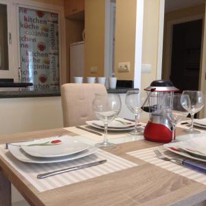 una mesa de madera con platos y copas de vino. en Benidorm La Cala Sidney, en Cala de Finestrat