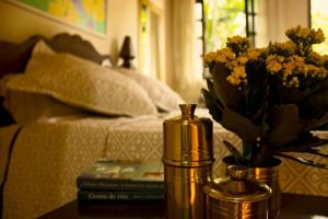 uma mesa com um vaso de flores ao lado de uma cama em Pouso Mel de Liz em Paraty