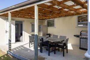 eine Terrasse mit einem Tisch, Stühlen und einem Grill in der Unterkunft Large Family Lakehouse in Mangakino