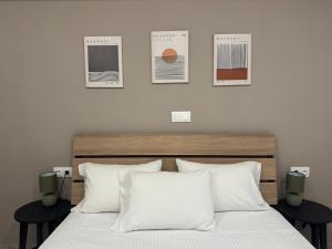 a bed with white pillows and posters on the wall at Remvi Apartment 3 in Armenistis